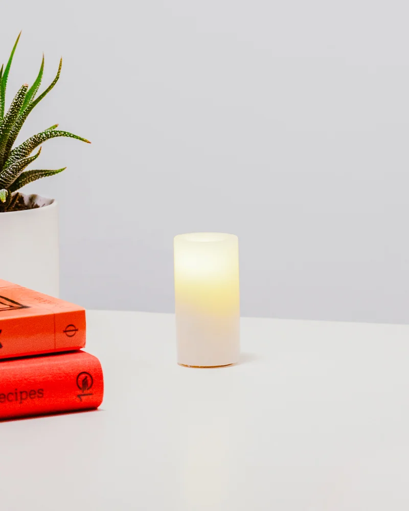 Real wax Context candle glowing beside books