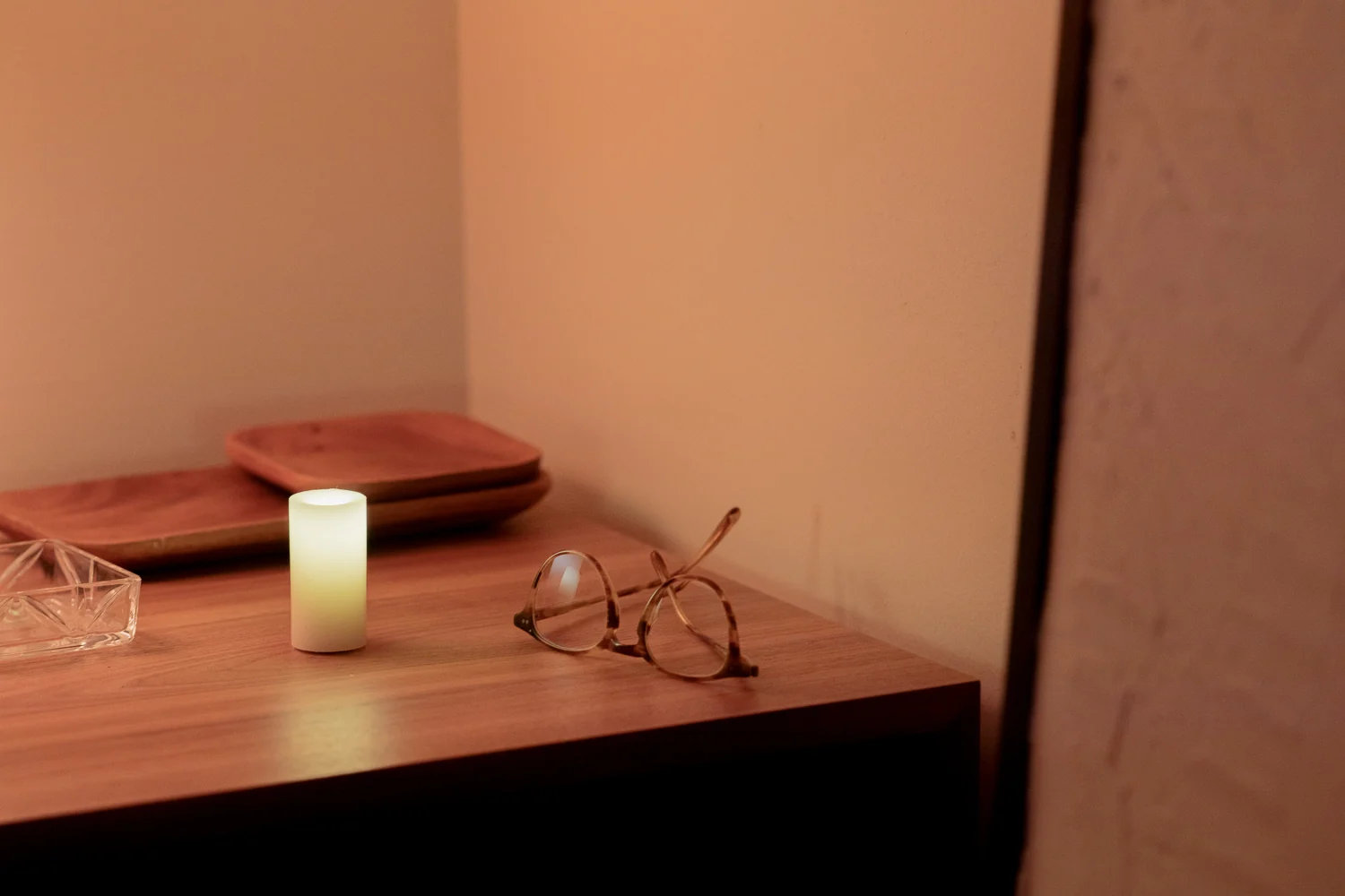 A glowing Context candle beside reading glasses on a wooden table