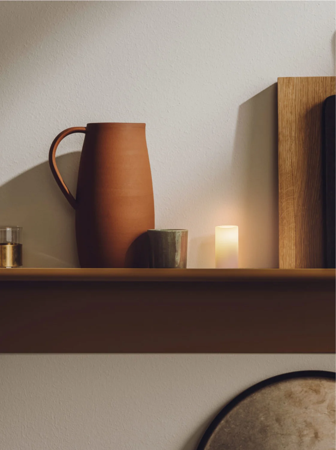 A glowing Context candle beside a ceramic pitcher