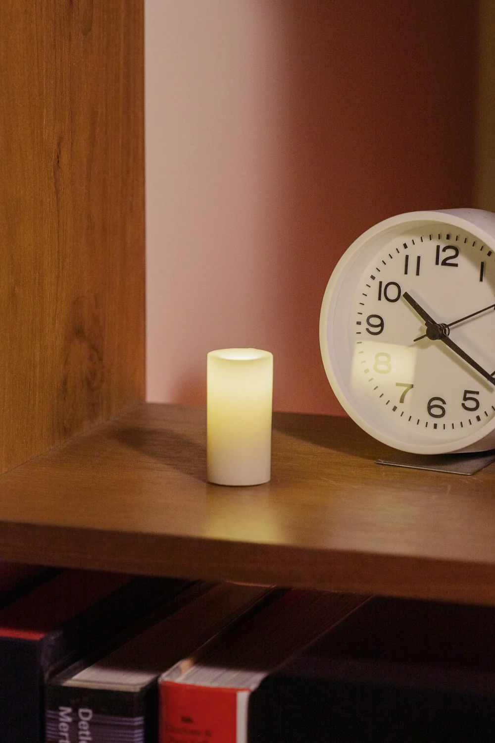 Close view of a glowing wax candle beside a clock